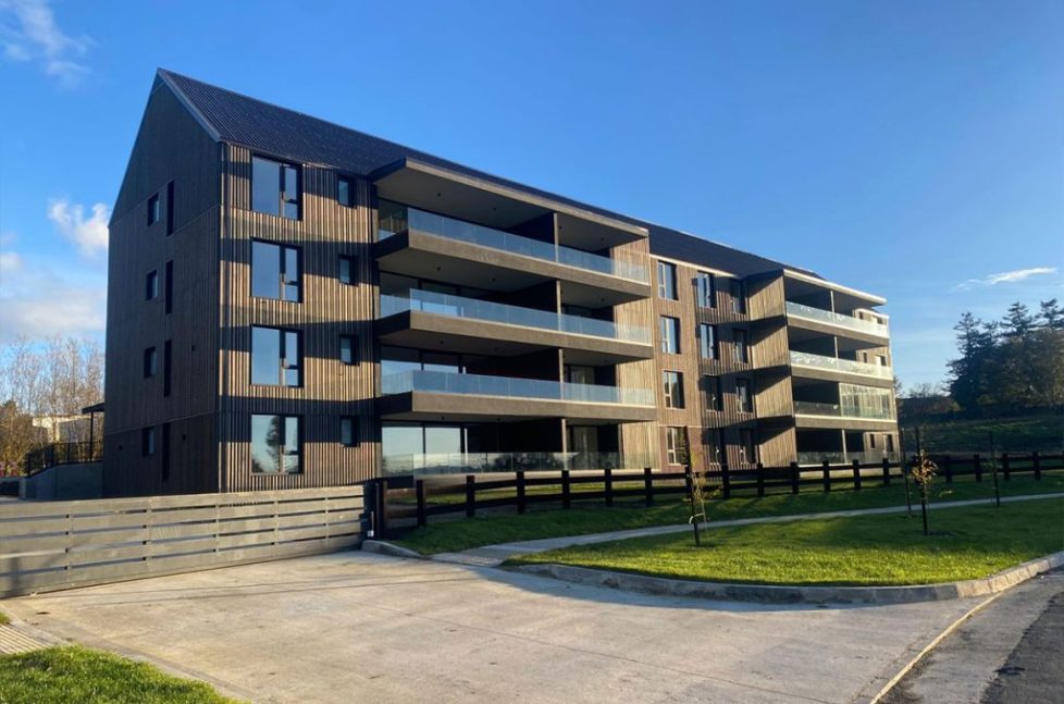 madero Edificio contemporáneo del proyecto Madero en Patagonia Virgin, con balcones de vidrio y fachada de madera clara.